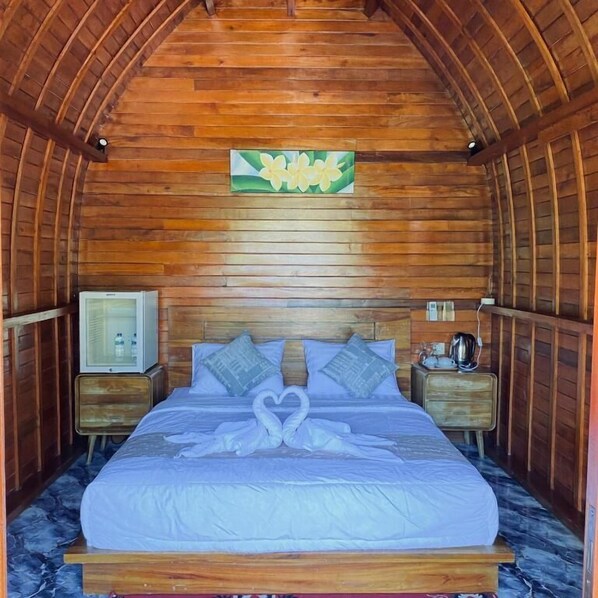 A wooden room with a bed, a nightstand, a television, and a wall-mounted light fixture.