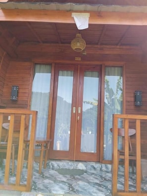 A wooden building with a porch, two doors with glass panels, and two small tables.