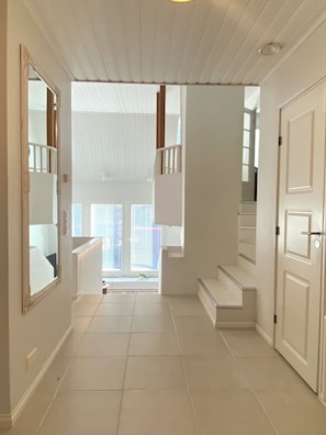 A hallway with a staircase leading to a second floor, white walls, and a tiled floor. - Scandinavian Arctic Retreat in Rovaniemi – 3BR & Sauna (Rovaniemi)