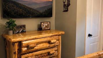 A room with a large painting of a sunset landscape, a wooden dresser with multiple drawers, a door, and a small decorative item on the wall.