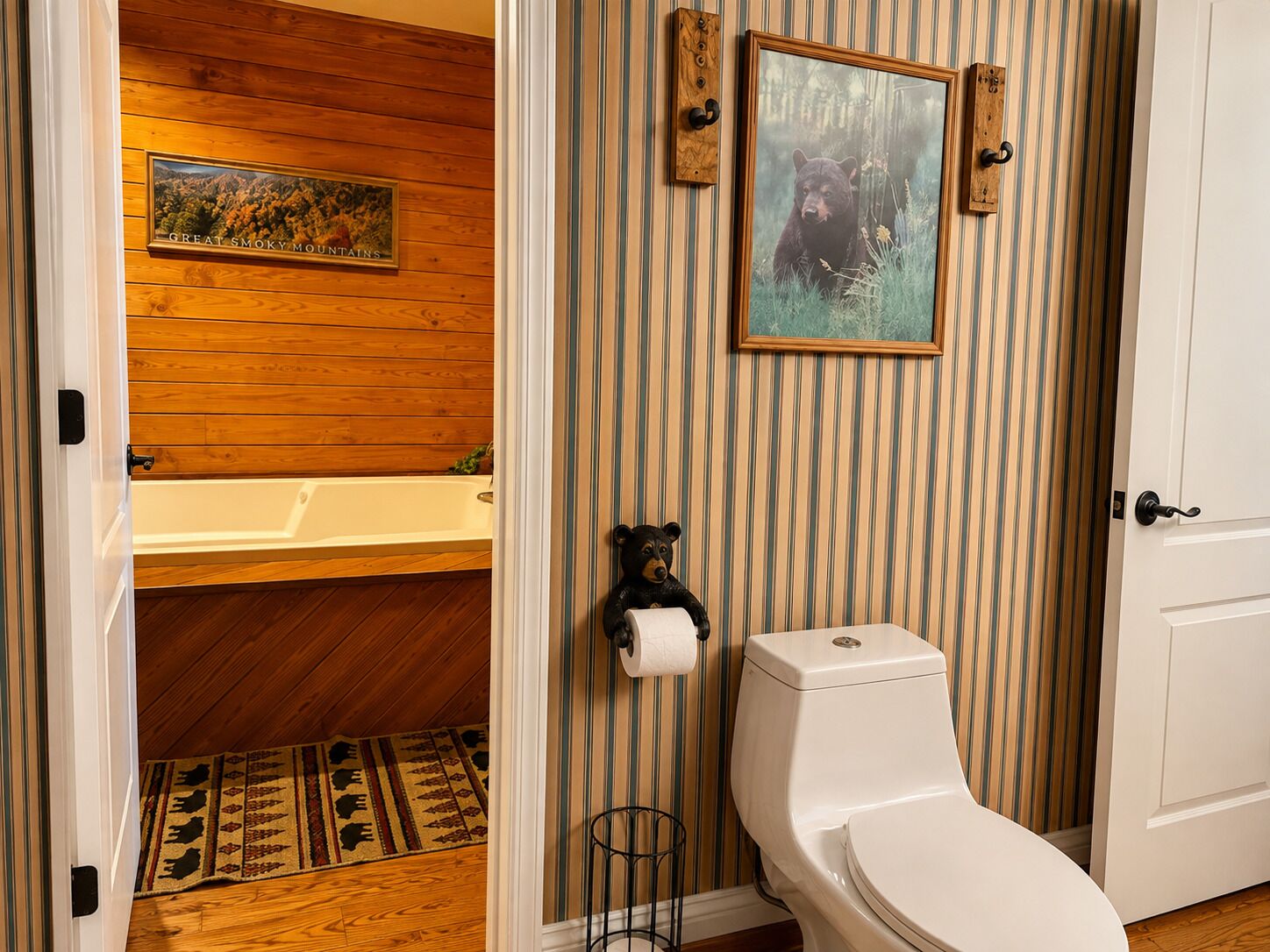 A bathroom with a wooden panel wall, a framed picture of a bear, a toilet, and a bathtub.
