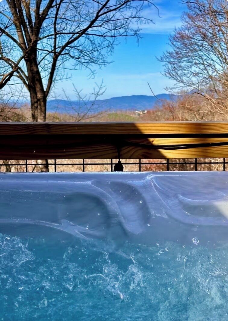Una piscina con plataforma de madera y vistas a montañas al fondo.