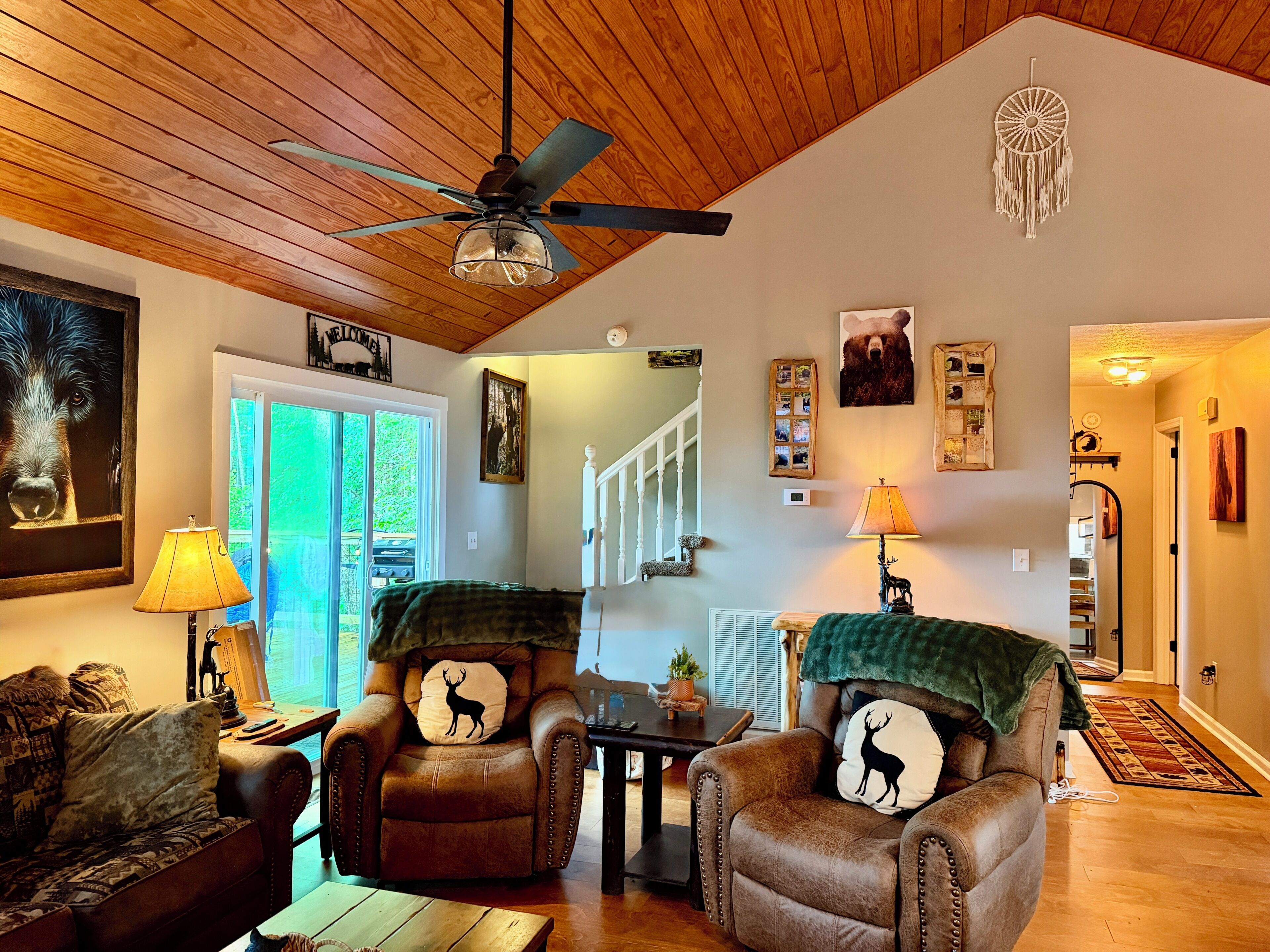 A cozy living room with leather armchairs, a ceiling fan, and a dreamcatcher on the wall.