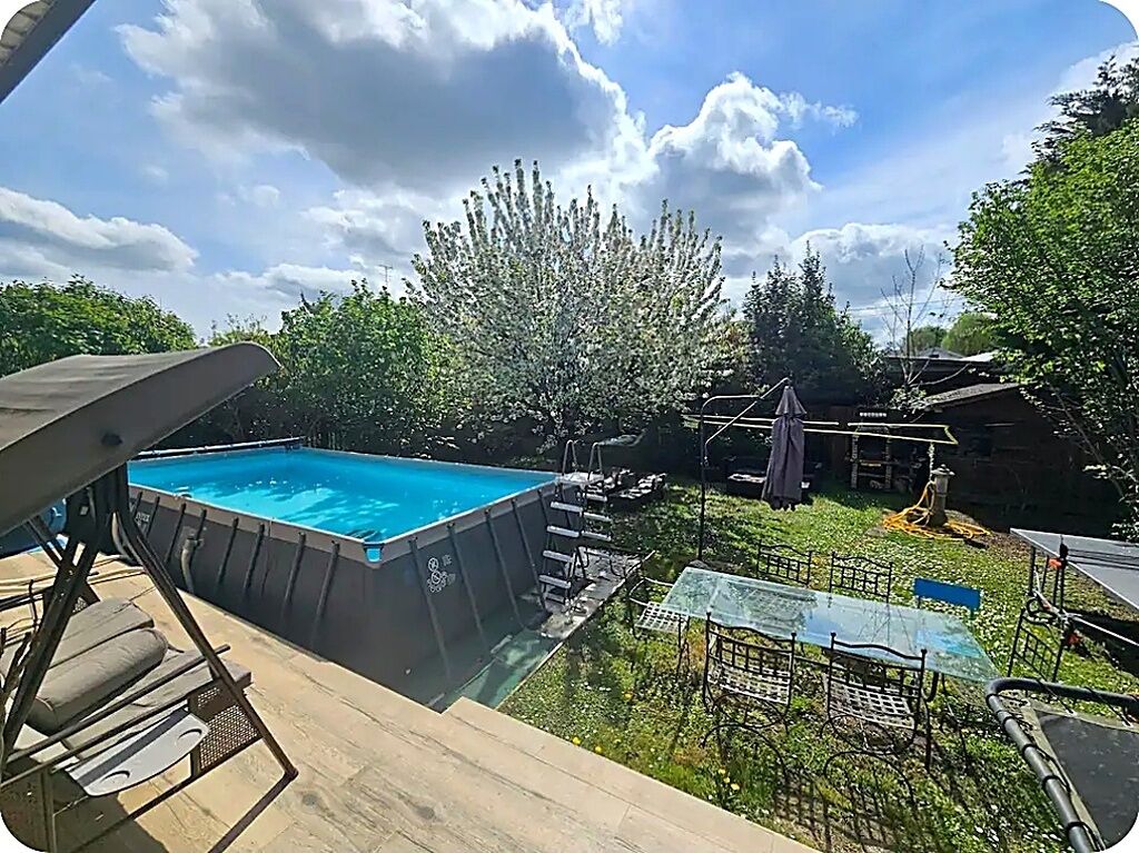 A backyard with a swimming pool, a wooden deck, and a metal table.