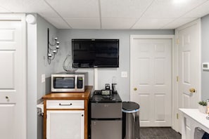 A compact kitchenette with a microwave, coffee maker, and refrigerator.