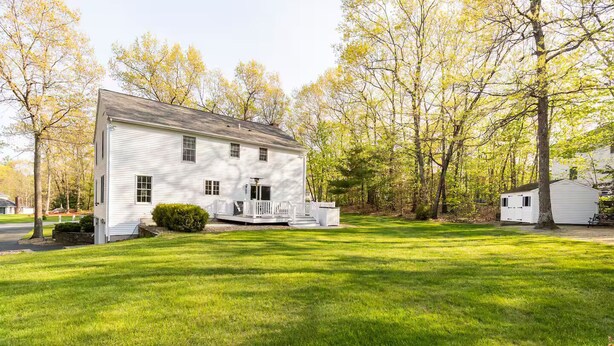 A white two-story house with a front porch, surrounded by a well-maintained lawn and trees.