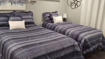 A bedroom with two beds, a painting, a sign, and a decorative wall piece.