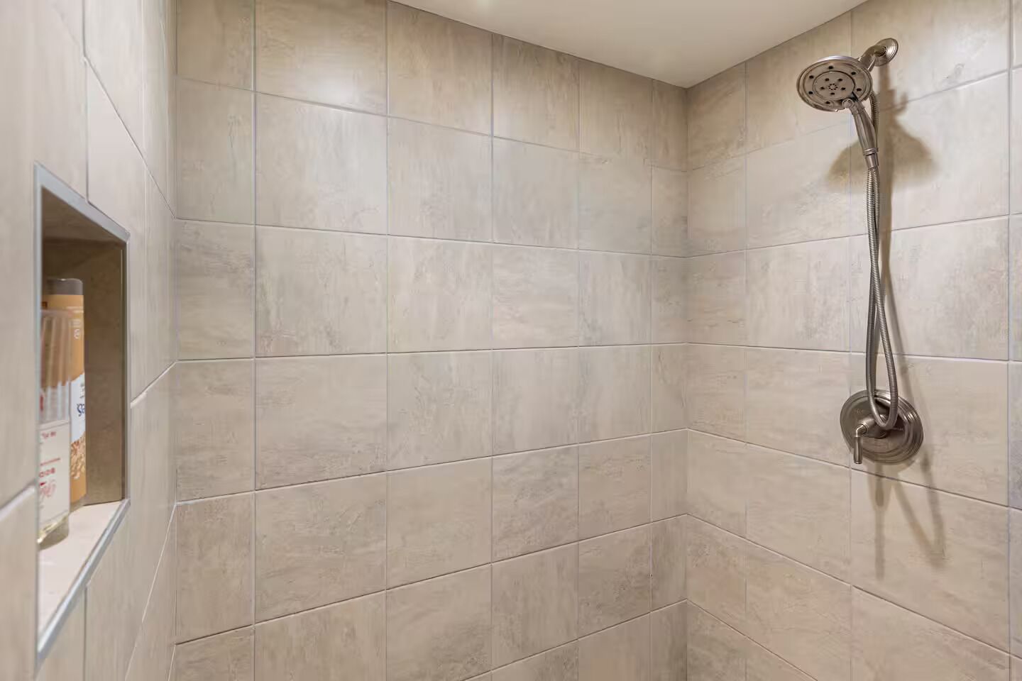 A shower area with a handheld showerhead mounted on the wall.