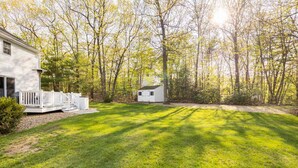 A residential property with a well-maintained lawn, a white house, and a small shed.