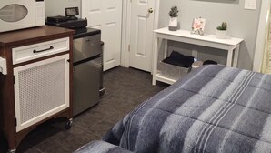 A room with two beds, a desk with a computer, a microwave, and a TV.
