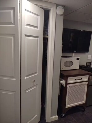 Une pièce avec une porte fermée, un téléviseur, un four à micro-ondes et un petit meuble.
