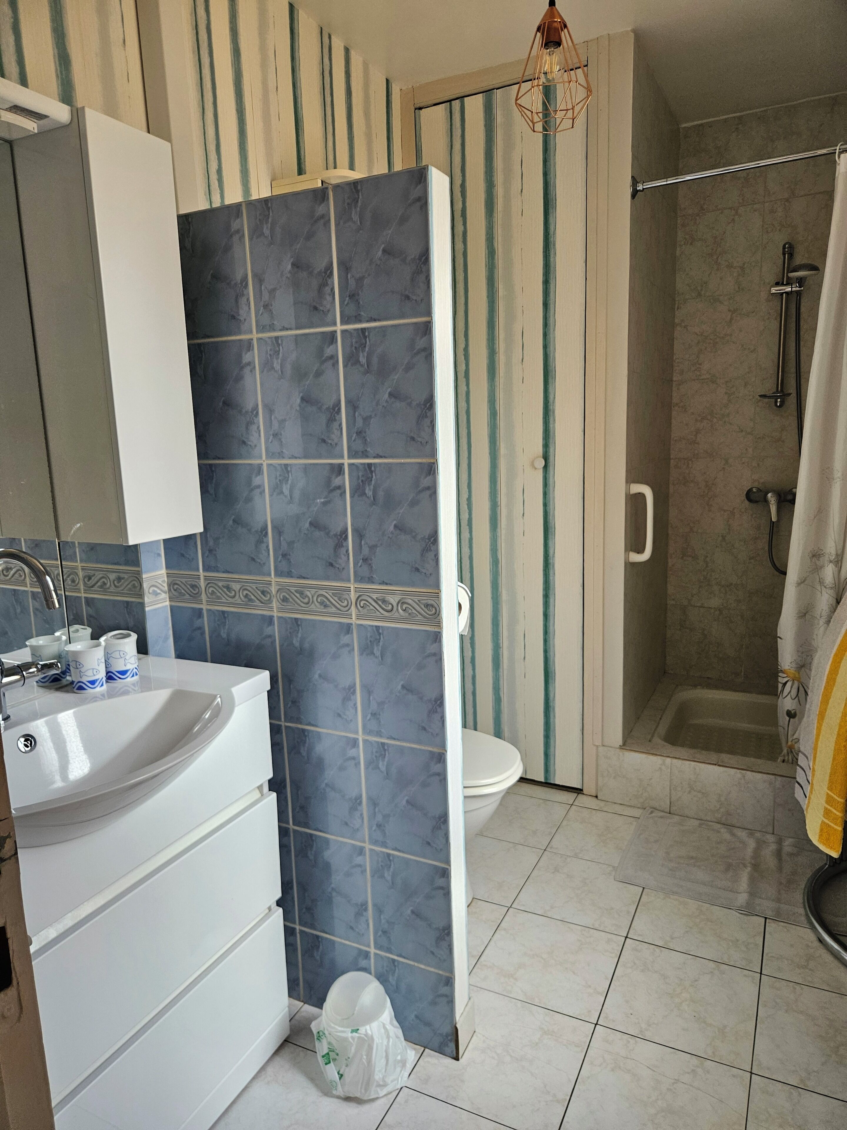 Ein Badezimmer mit weißem Waschbecken, Toilette und Duschbereich.