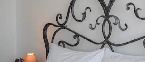 A bed with a metal headboard, a bedside table with a lamp, and a framed picture on the wall.