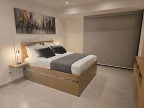 A modern bedroom with a bed, bedside table, and a painting on the wall.