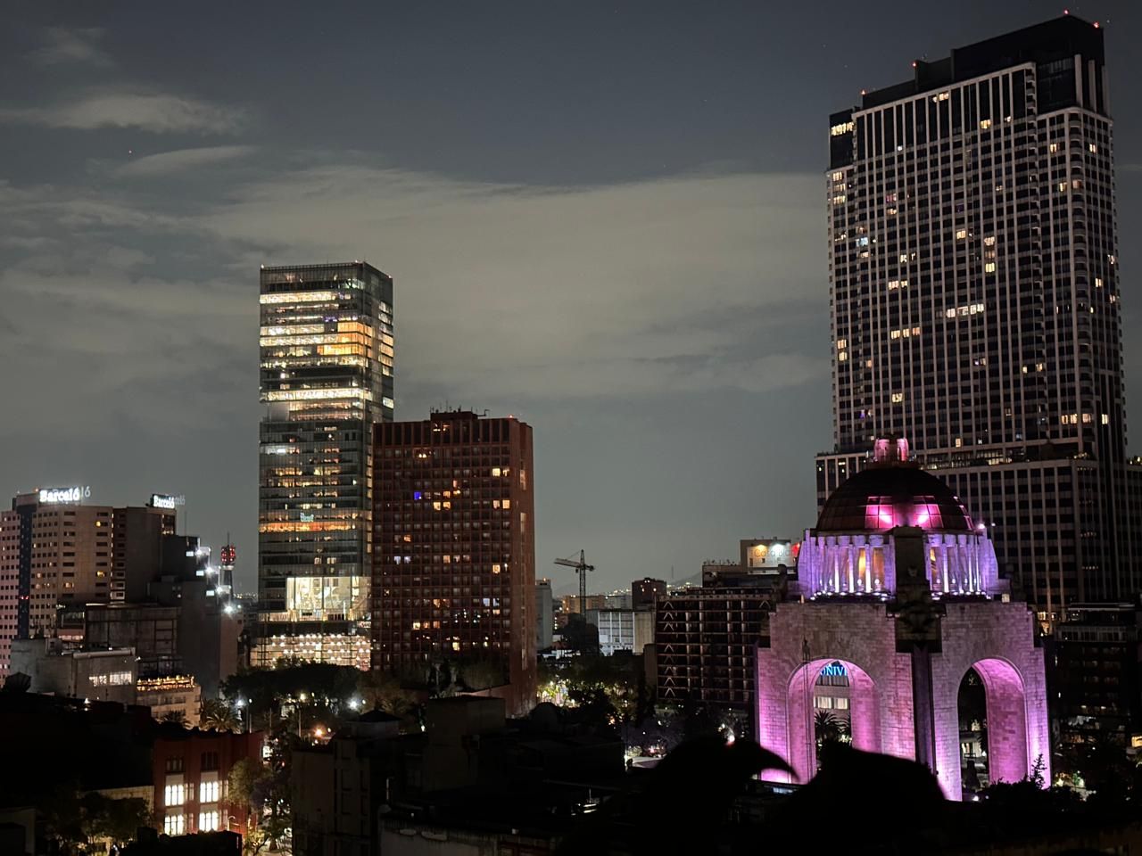 Une vue nocturne d’une ville, avec des bâtiments illuminés et une arche imposante.