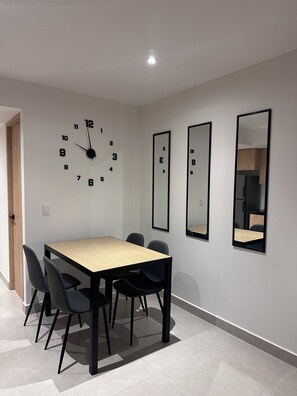 A modern dining area with a wooden table, black chairs, and a wall clock. - Loft very close to the Monument to the Revolution, Reforma, and Insurgentes (Ciudad de México)