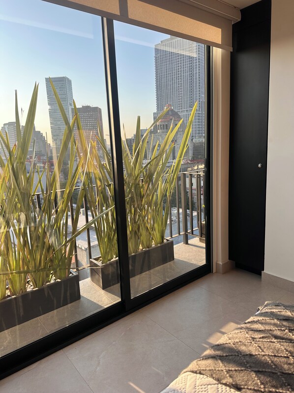 A modern room with large windows, a bed, and potted plants.