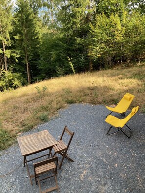 A gravel area with a wooden table and chairs, and a yellow lounge chair. - Morvan-style caravan (Dun-les-Places)