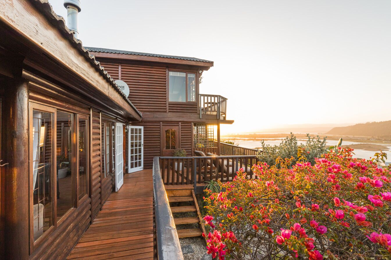 Une cabane en bois dotée d’un balcon donnant sur une étendue d’eau.