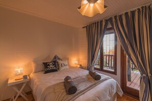 Ein Hotelzimmer mit einem Bett, zwei Nachttischlampen, einem Fenster mit Vorhängen und Blick nach draußen.