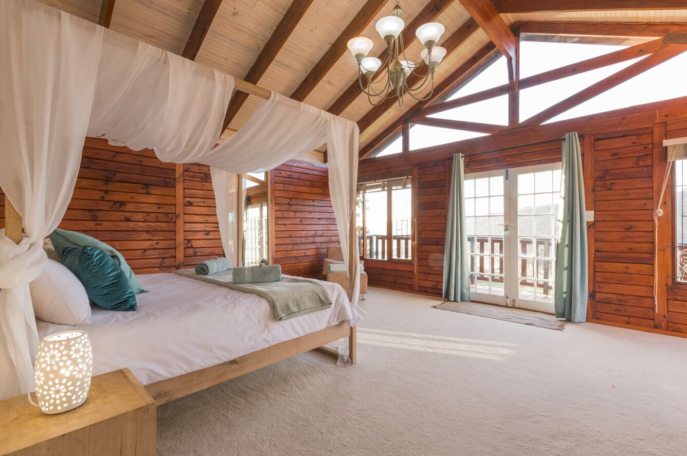 Un dormitorio de cabaña de madera con una cama con dosel, una mesita de noche y una lámpara.