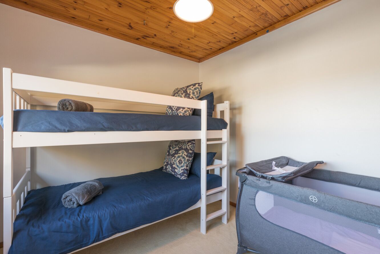 A bunk bed room with a small desk and a chair.