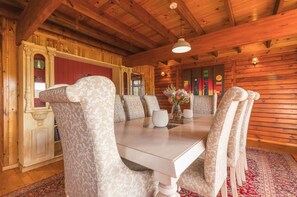 Ein Essbereich mit Holzboden, einem weißen Tisch, gemusterten Polstersesseln und einer roten Wand.