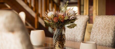 A table with a vase of flowers and two white cups.