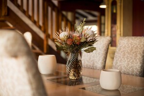 A table with a vase of flowers and two white cups.