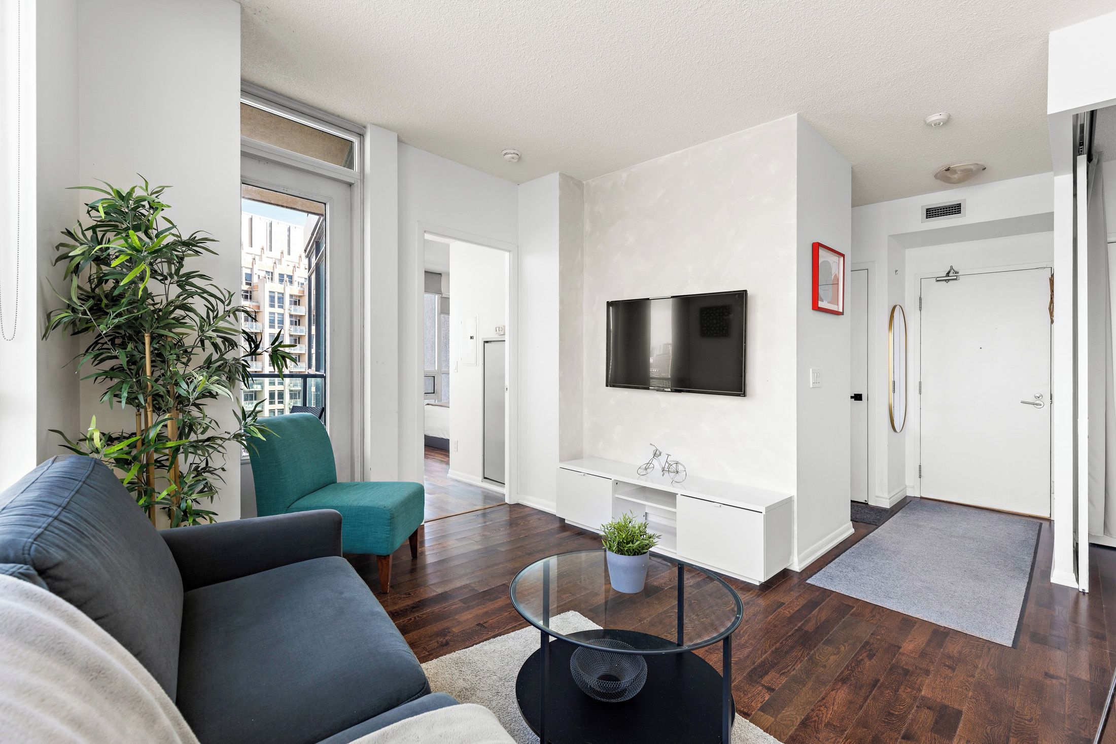 A modern living room with a sofa, teal chair, and a coffee table.