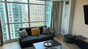 A modern living room with a sofa, a coffee table, and a view of high-rise buildings.
