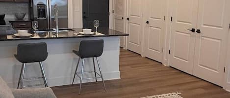 A modern kitchen with a central island, bar stools, and pendant lighting.