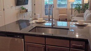 A kitchen with a central island, dark cabinetry, and pendant lighting. - Resort-Style Stay | Pool, Gym | Near Toyota Field (Madison)