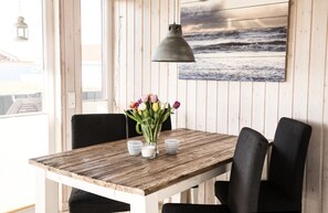A wooden table with a vase of tulips, two cups, and a lamp in a room with a wooden wall and a beach view. - Deichperle Vacation Home: No security deposit, no final cleaning fee, no energy costs (Wesselburenerkoog)