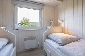A room with two beds, a window, a radiator, and a small table with a lamp. - Deichperle Vacation Home: No security deposit, no final cleaning fee, no energy costs (Wesselburenerkoog)