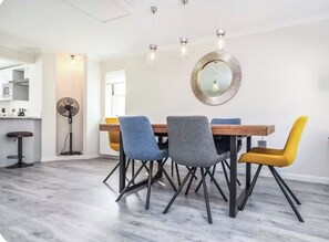 Ein Essbereich mit einem Holztisch, vier Stühlen und einem runden Spiegel an der Wand.