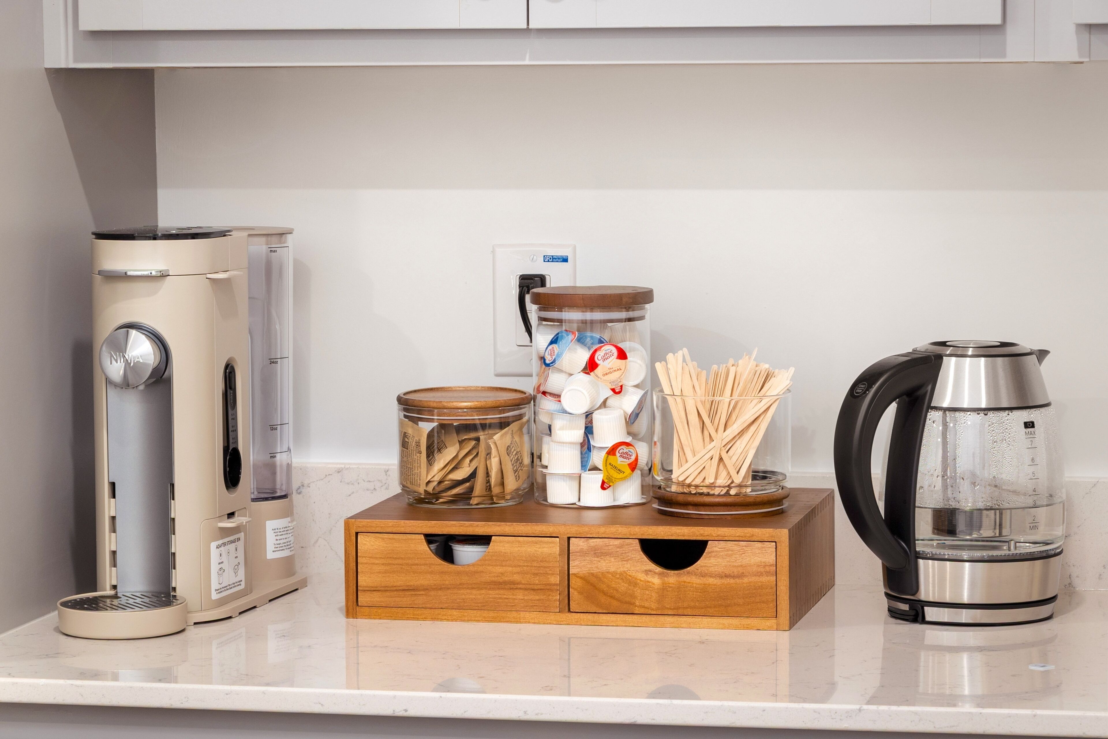 A kitchen with a coffee maker, a kettle, and storage containers on the counter.