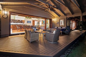 A spacious outdoor deck with a dining area, seating, and a view into the interior. - Island Time Retreat by Gather: Oceanfront Access (Kamuela)
