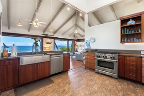 A spacious kitchen with a large island, a built-in oven, and a view of the ocean. - Island Time Retreat by Gather: Oceanfront Access (Kamuela)