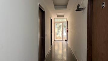 A hallway with doors on both sides, a fire extinguisher mounted on the wall, and a number sign above a door.