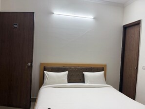 A hotel room with a bed, a wooden door, and a light fixture. - Classic Murshidabad Junction (Lalbag)