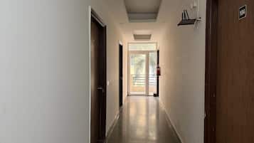 A corridor with doors on both sides, a fire extinguisher mounted on the wall, and a door with the number 104.