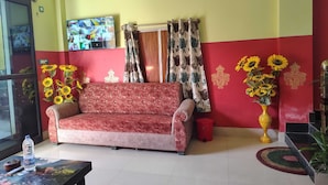 A living room with a sofa, a television mounted on the wall, and a red and yellow wall design.