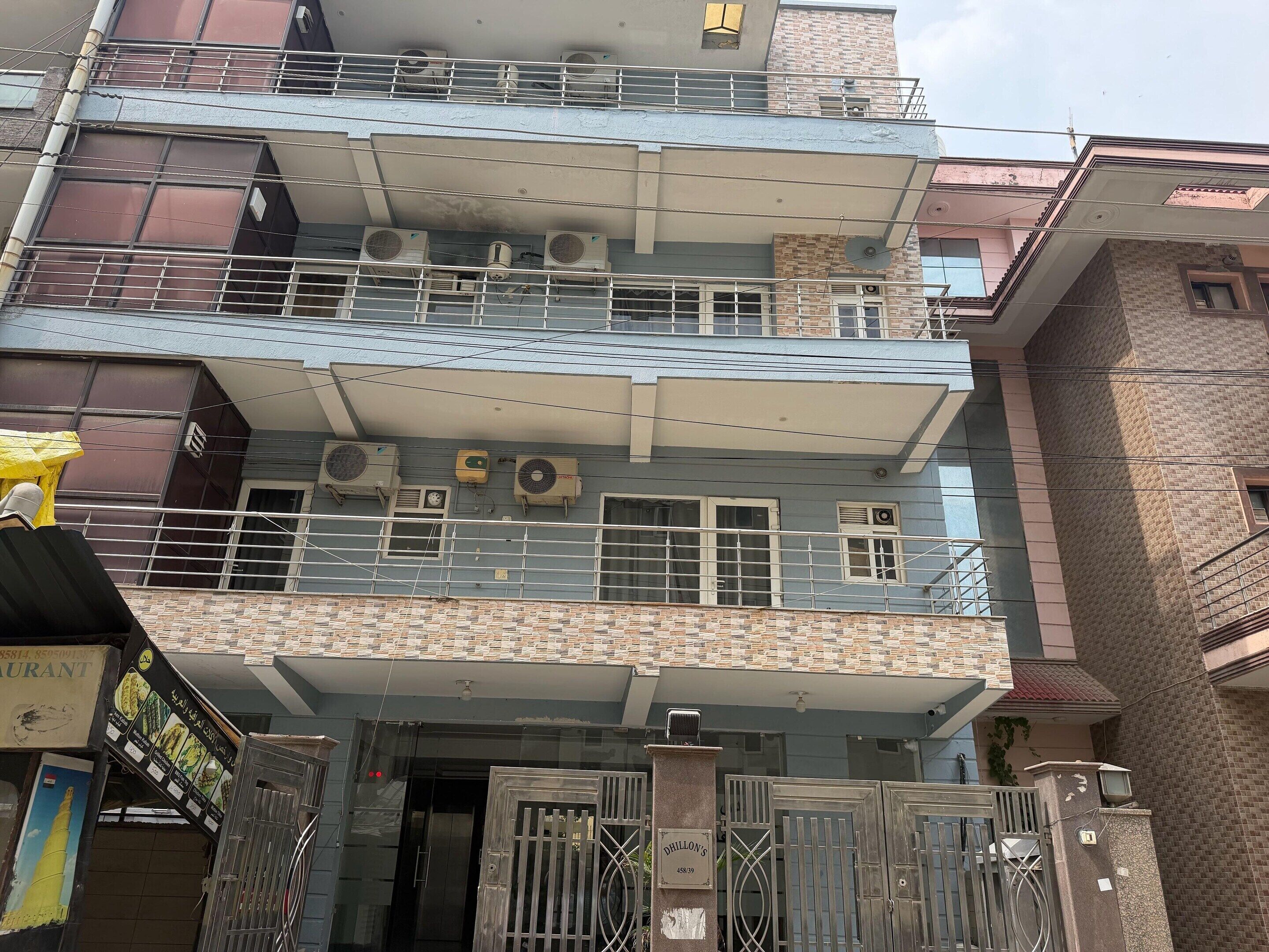 A multi-story building with balconies, air conditioning units, and a gated entrance.
