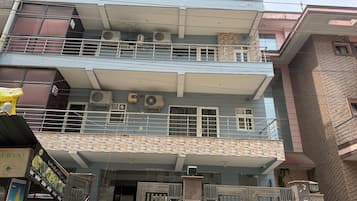 A multi-story building with balconies, air conditioning units, and a gated entrance.