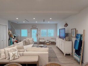 A spacious living room with a sofa, chairs, a television, and a staircase. - Paradise Found~ Oceanfront Home in Key Largo, FL (Key Largo)