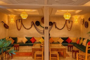 A room with a sofa set, wooden furniture, and wall-mounted lights. - Ourika, Riad Belikoss Pool and Spa (Marrakech)