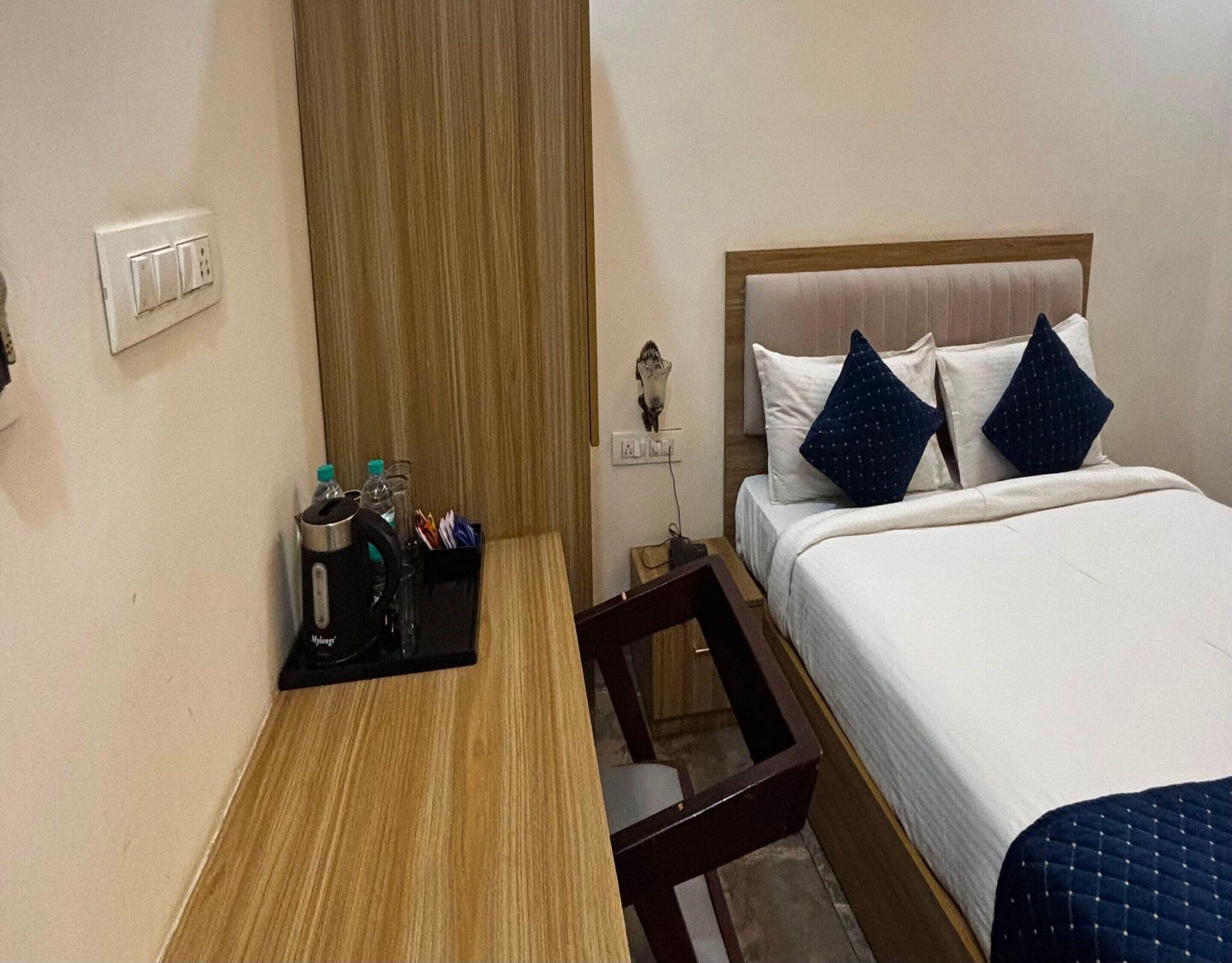 A hotel room with a bed, bedside table, and a nightstand.