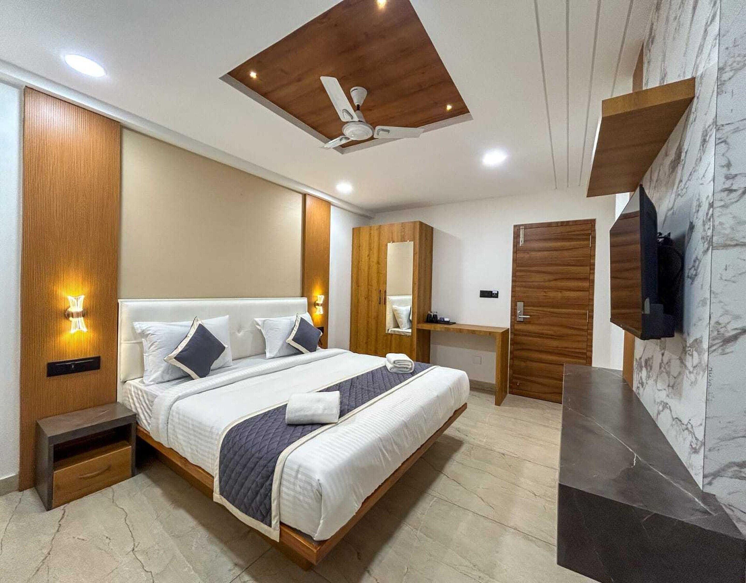 A modern bedroom with a large bed, bedside tables, a wardrobe, a mirror, and a ceiling fan.