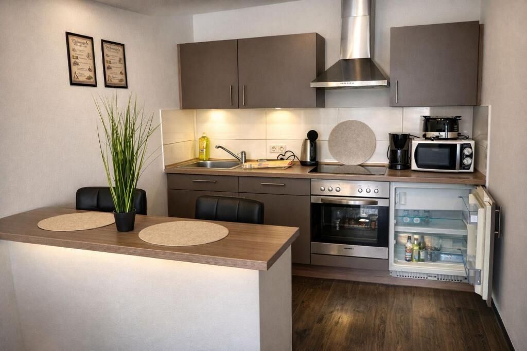A modern kitchen with a central island, stainless steel appliances, and a built-in oven.